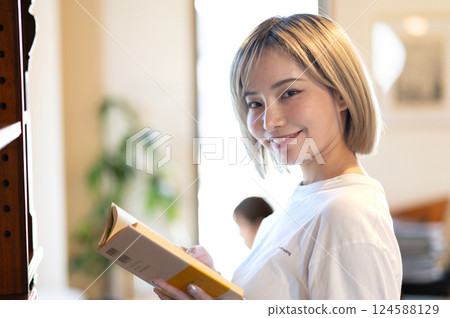 Woman reading a book in front of a bookshelf 124588129
