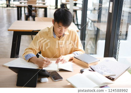 Student studying online and preparing for exams with digital devices and books Student studying online and preparing for exams with digital devices and books 124588992