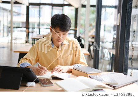 Student studying online and preparing for exams with digital devices and books 124588993