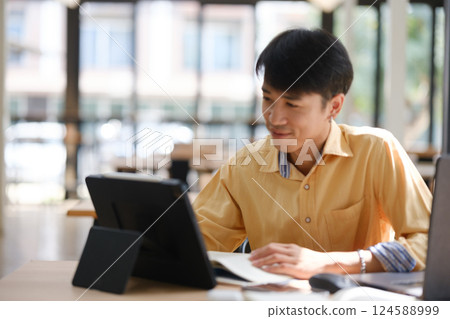 Student studying online and preparing for exams with digital devices and books Student studying online and preparing for exams with digital devices and books 124588999