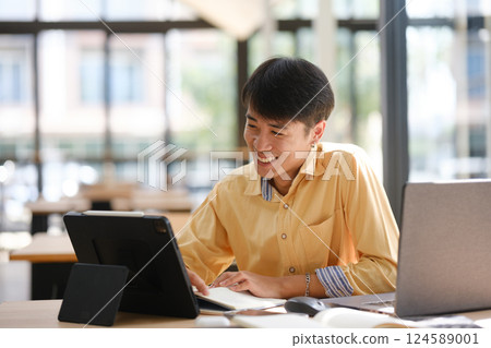 Student studying online and preparing for exams with digital devices and books Student studying online and preparing for exams with digital devices and books 124589001