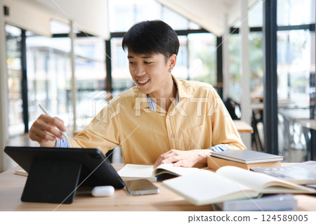 Student studying online and preparing for exams with digital devices and books 124589005