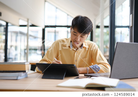 Student studying online and preparing for exams with digital devices and books 124589014