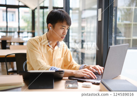 Student studying online and preparing for exams with digital devices and books Student studying online and preparing for exams with digital devices and books 124589016