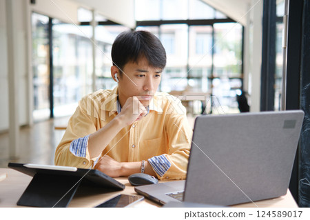Student studying online and preparing for exams with digital devices and books Student studying online and preparing for exams with digital devices and books 124589017