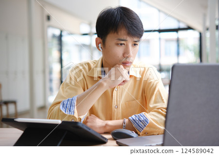 Student studying online and preparing for exams with digital devices and books 124589042