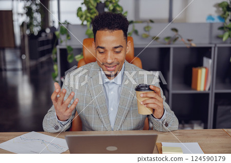 A Businessman Actively Engaging in a Virtual Meeting While Enjoying a Cup of Coffee 124590179