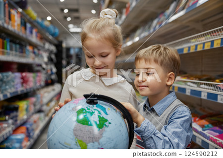 Little children choosing globe earth model at stationery store Little children choosing globe earth model at stationery store 124590212