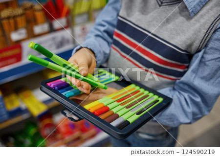 Closeup hands of unrecognizable boy holding colorful markers in pack Closeup hands of unrecognizable boy holding colorful markers in pack 124590219