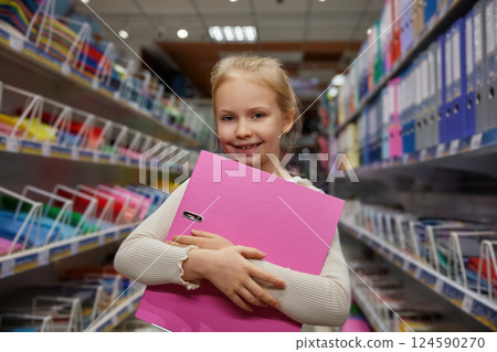 Portrait of attractive little schoolgirl holding cute folder for papers in hands Portrait of attractive little schoolgirl holding cute folder for papers in hands 124590270