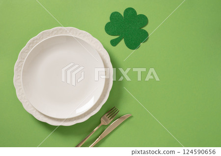 St Patrick's Day table setting with white plate and clover leaf on green. 124590656