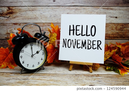 Hello November text with alarm clock and maple leaf decoration on wooden background 124590944