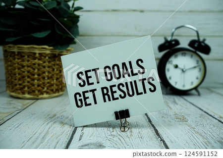 Set Goals Get Results text on paper card with alarm clock on wooden background 124591152