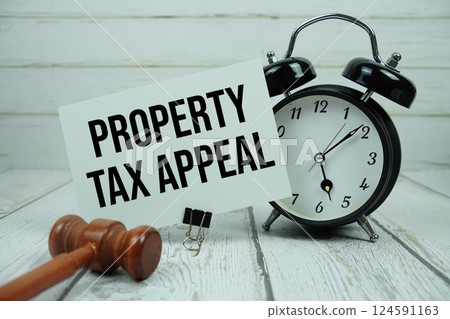 Property Tax Appeal text on paper card with alarm clock and wooden judge gavel on wooden background 124591163