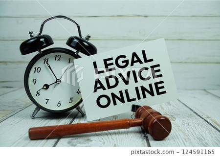 Legal Advice Online text on paper card with alarm clock and wooden judge gavel top view on wooden background 124591165