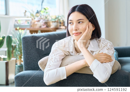 Smiling woman lying on sofa in living room Smiling woman lying on sofa in living room 124591192