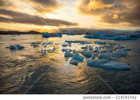 Icebergs floating in Jokulsarlon glacier lagoon lake at sunset Icebergs floating in Jokulsarlon glacier lagoon lake at sunset 124591542