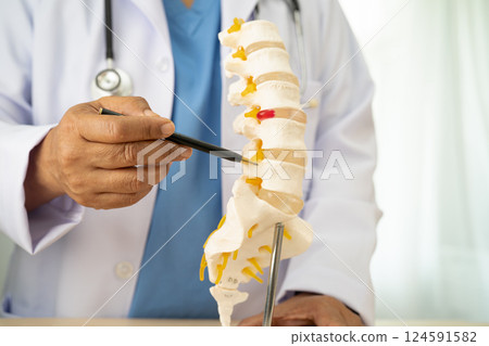 Doctor with lumbar vertebra bone skeleton and nerve model for treatment in the orthopedic department. Doctor with lumbar vertebra bone skeleton and nerve model for treatment in the orthopedic department. 124591582