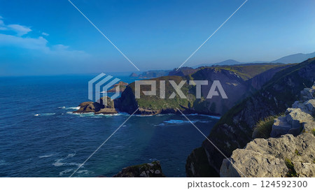 Stunning coastal cliffs overlooking the deep blue sea with distant rock formations and rolling hills. Stunning coastal cliffs overlooking the deep blue sea with distant rock formations and rolling hills. 124592300