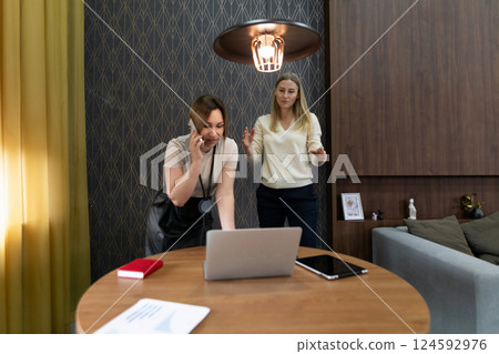 Two women engaged in a collaborative work session in a modern office setting during daytime Two women engaged in a collaborative work session in a modern office setting during daytime 124592976