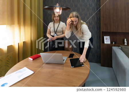 Women collaborating in a modern workspace while preparing for a meeting in a cozy interior setting Women collaborating in a modern workspace while preparing for a meeting in a cozy interior setting 124592980