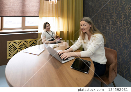 Focused women engaged in work and discussion in a modern office setting during daytime 124592981