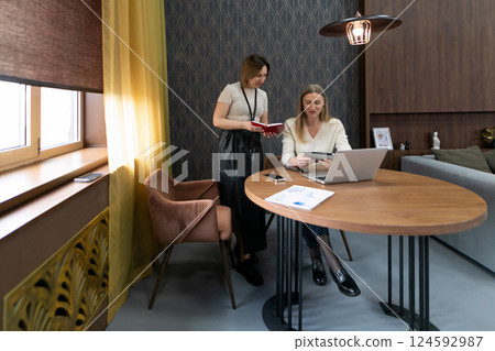 Collaboration in a modern workspace between two women discussing ideas at a round table during Collaboration in a modern workspace between two women discussing ideas at a round table during 124592987
