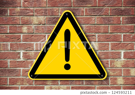 Yellow caution triangle sign on a brick wall 124593211