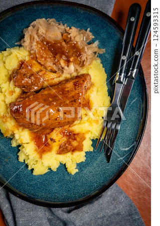 Braised pork ribs with spicy sauce served with mashed potatoes and sauerkraut. 124593315