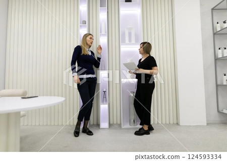 Two women discussing business in a modern showroom with minimalist design and elegant decor Two women discussing business in a modern showroom with minimalist design and elegant decor 124593334