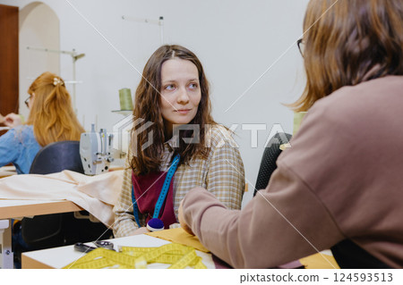 Three women seamstresses and fashion designers work in for sewing machines, clothing production. 124593513