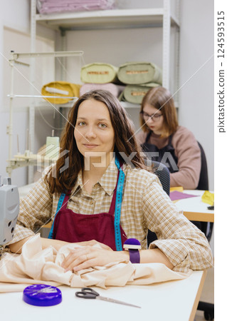 Two female seamstresses and fashion designers work at sewing machines, clothing production. 124593515