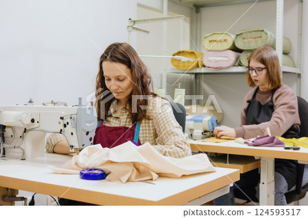 Two female seamstresses and fashion designers work at sewing machines, clothing production. 124593517