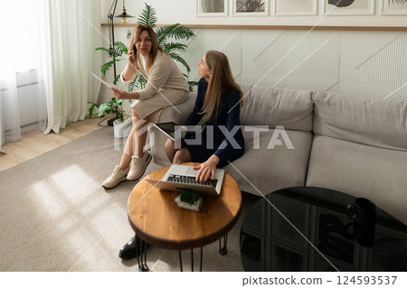 Professional women collaborating in a modern living room during a business discussion 124593537