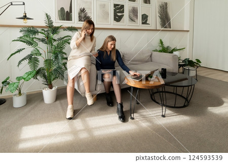 Two women engaged in a productive discussion in a modern living space decorated with greenery and Two women engaged in a productive discussion in a modern living space decorated with greenery and 124593539