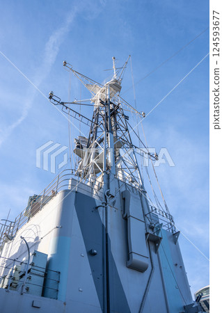 A striking view of the foremast on HMS Belfast, prominently displayed against a clear blue sky. The historic warship is docked in London, attracting visitors interested in naval history. 124593677