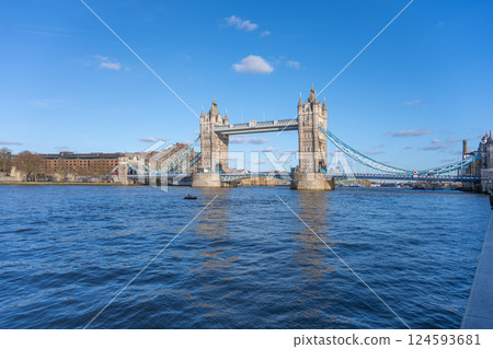 Tower Bridge showcases its magnificent architecture against a clear blue sky. The river reflects the bridge's grandeur, while boats gently navigate the waters. Tower Bridge showcases its magnificent architecture against a clear blue sky. The river reflects the bridge's grandeur, while boats gently navigate the waters. 124593681