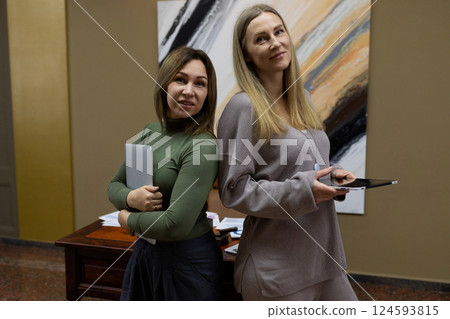 Two women pose confidently in an office setting while engaged in a professional discussion during a Two women pose confidently in an office setting while engaged in a professional discussion during a 124593815