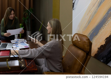 Colleagues collaborating in a modern office space while reviewing documents and using a smartphone 124594194