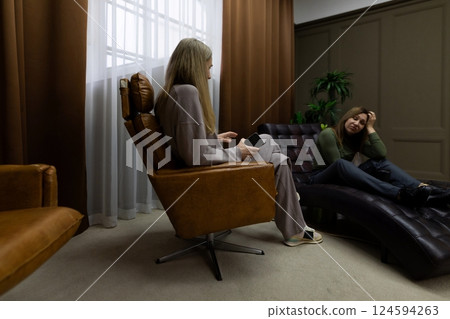 Two women engaged in serious conversation in a cozy room with modern decor and therapeutic Two women engaged in serious conversation in a cozy room with modern decor and therapeutic 124594263