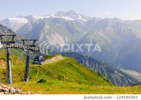 Scenic cable car glides lush valley with towering metal columns along scenic Grossglockner Alps Tyrol valley mountains. Panoramic view  sweeping alpine vistas stunning journey high above terrain 124594303