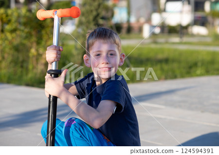 Boy with diabetes riding a scooter, smiling at the camera, glucose sensor visible. 124594391
