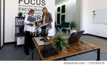 Two professionals collaborate in a modern office space promoting focus and encouragement 124594428