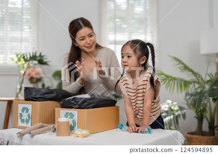 Sustainability and Family Education. A mother and daughter engage in recycling activities, fostering environmental awareness together. 124594895