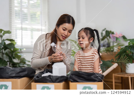 Engaging in Recycling and Family Bonding. A mother demonstrates the importance of recycling to her daughter through hands-on activities in their home. 124594912