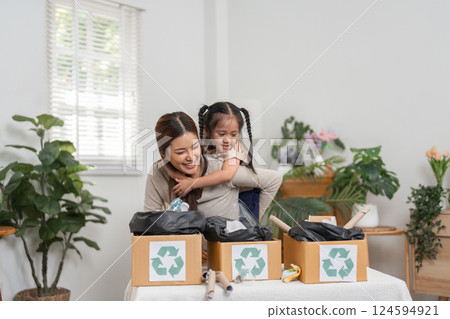 Sustainability and Family Engagement. A mother and daughter enjoying a playful recycling activity together at home. 124594921