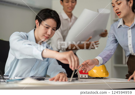 Team Collaboration and Planning. Professionals devising a construction project strategy together with blueprints in an office setting. Team Collaboration and Planning. Professionals devising a construction project strategy together with blueprints in an office setting. 124594959