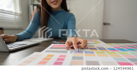 Color Exploration and Digital Design. A professional evaluating vibrant color choices using swatches and a laptop. Color Exploration and Digital Design. A professional evaluating vibrant color choices using swatches and a laptop. 124594961