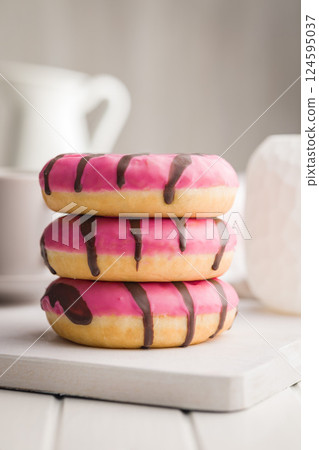 Sweet pink donut with chocolate strips on white table. Sweet pink donut with chocolate strips on white table. 124595037