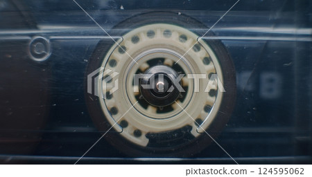 Macro Close Up of Magnetic Tape Reel on Audio Cassette Tape Spinning, Playing Old Music 124595062